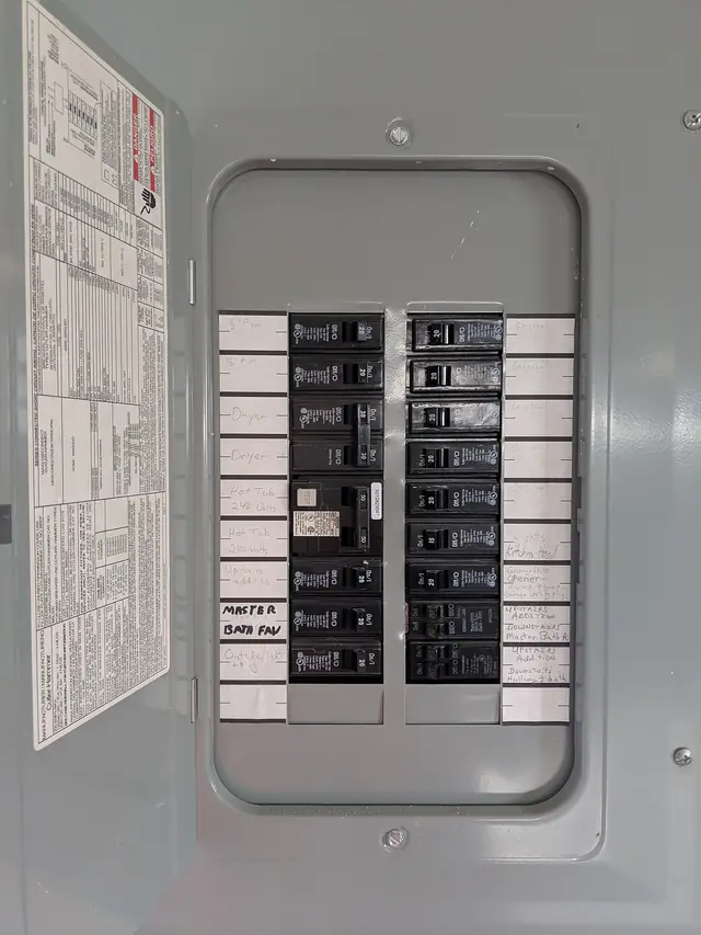 An open residential breaker panel with labelled circuit breakers