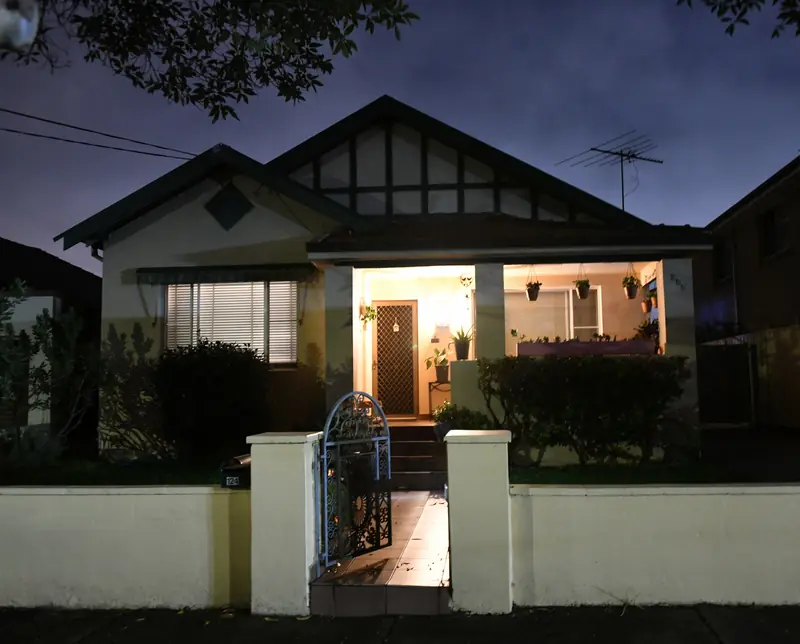 A bungalow at dusk with a warmly lit front porch and windows