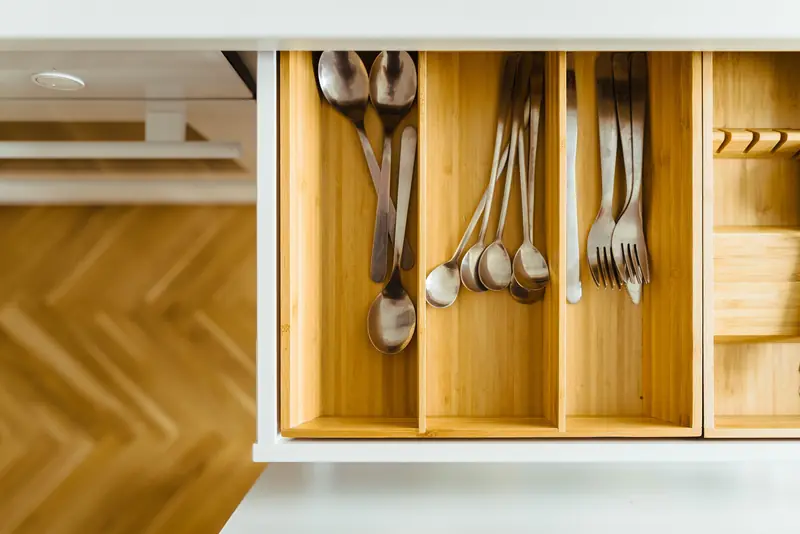 An open kitchen drawer with neatly sorted cutlery in wooden dividers