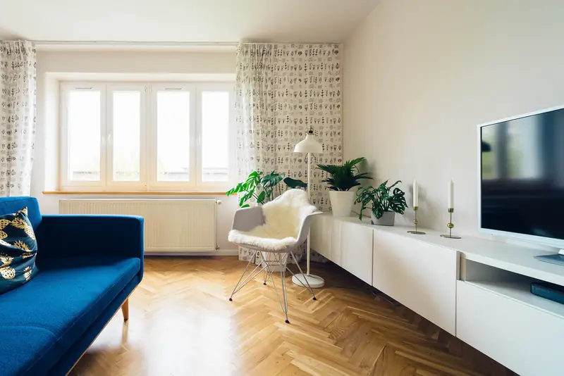 A bright, tidy living room with a blue sofa, plants and a herringbone floor