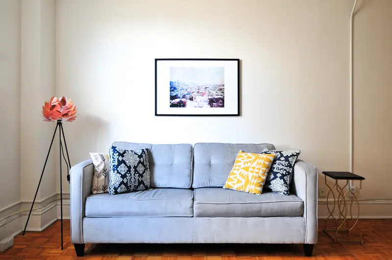 A pale blue sofa with patterned cushions against a white wall