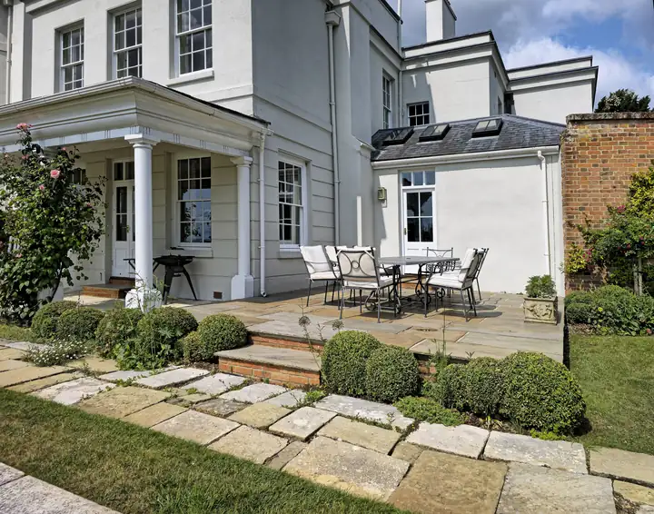 Stone stepping slabs crossing a lawn toward a paved patio
