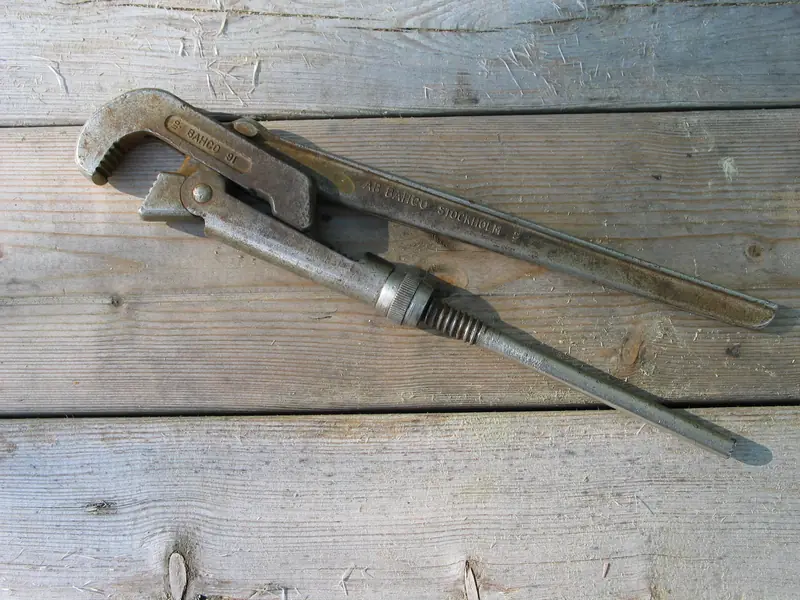 A well-used pipe wrench lying on weathered wooden boards